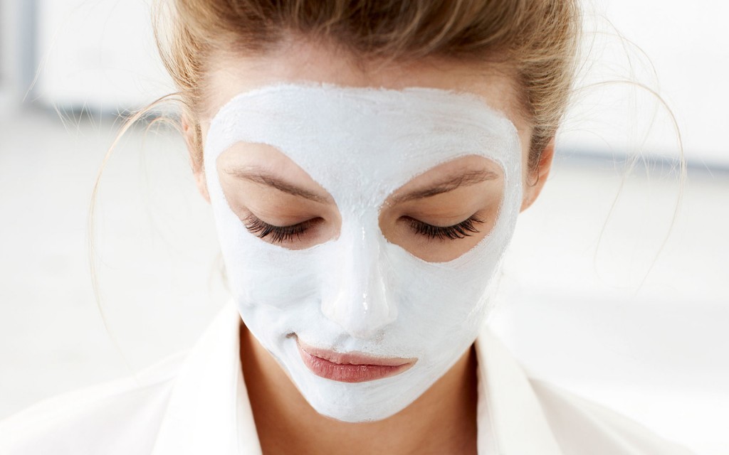 Woman with facial mask using cell phone