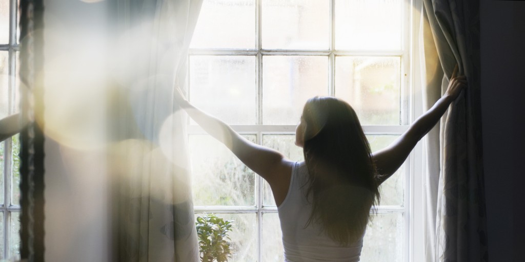 woman opening curtains in the morning